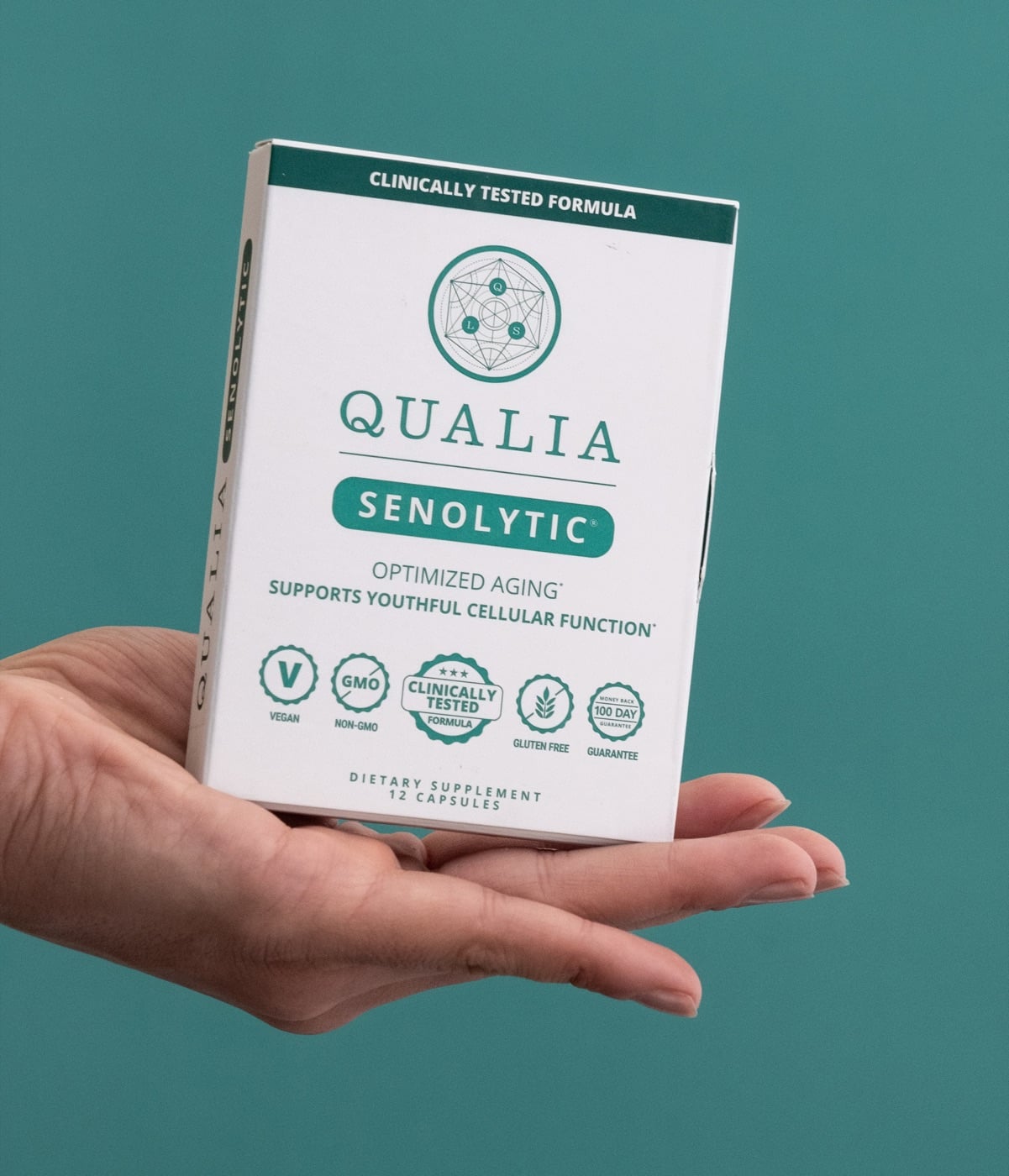 Hand holding Qualia Senolytic box against a teal background